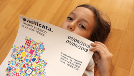 Poster della mostra su Mauro Bubbico tenuto in mano 